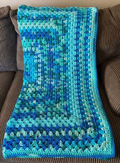 a blue crocheted blanket sitting on top of a couch