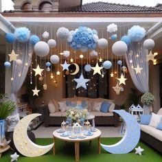 an outdoor living room decorated for a baby's first birthday with moon and stars hanging from the ceiling