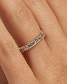 a woman's hand with a wedding band on her finger, wearing a diamond ring