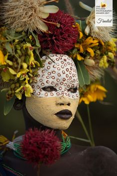 a woman's head is adorned with flowers and leaves in the shape of a face