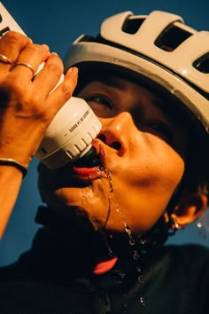 a close up of a person wearing a helmet drinking from a water bottle