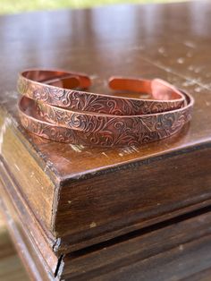 These bracelets are made from hand embossed vintage copper. Each one is unique! The floral pattern is present on each bracelet, but no two are alike! 🌸 See other listing for matching items!🫶🏻 Handmade Vintage Copper Bracelets, Vintage Copper Bracelet As Gift, Copper Etched Bracelets As A Gift, Vintage Copper Bracelet For Gift, Adjustable Etched Bronze Bracelets, Vintage Copper Bracelet Gift, Handmade Rose Gold Copper Cuff Bracelet, Vintage Hand Tooled Bracelets For Gift, Engraved Bronze Copper Bracelets