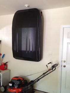 a room with a lawn mower on the floor and a wall hanging above it