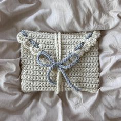 a crocheted blanket with a blue bow on the front and white trim around it