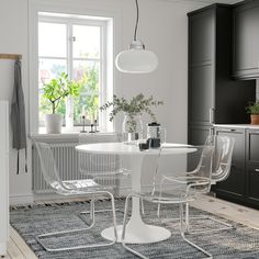 a white table and four chairs in a room with black cupboards on the wall