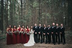 a group of people standing in front of trees wearing red and black outfits with bouquets