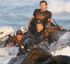 two men are riding on a raft in the water while another man is standing behind them