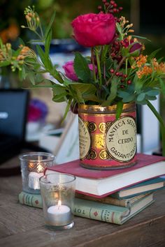 a vase filled with flowers sitting on top of a table next to candles and books