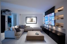 a living room with couches and televisions on the wall in front of it