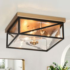 a light fixture in a white room with a mirror and potted plant on the table