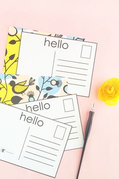 three postcards sitting on top of each other next to a pen and yellow flower