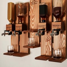 three wooden shelves with different types of drinks and glasses hanging on the wall next to each other