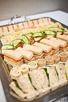 an assortment of sandwiches and cucumbers on a tray