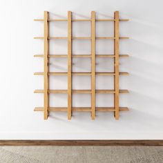 a wooden book shelf mounted to the side of a white wall next to a rug