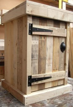 a wooden box sitting on top of a floor next to a table with drawers in it