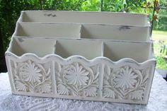 a set of four white planters sitting on top of a lace covered table cloth