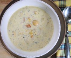 a bowl filled with soup on top of a table next to a fork and spoon