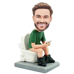 a bobble head sitting on top of a toilet with a cell phone in his hand