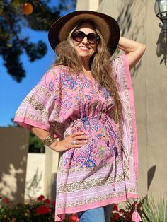 Our Rosa Tropicale short kaftan dress or top will transport you and everyone around you to the tropics with just one look! The pink ground colour of this print reminds us of the English cabbage roses that grow in Jean Marie's garden on the beautiful Isle of Wight in the UK. Hence the name ROSA, however with a TROPICALE twist. This intricate botanical hand block print is certain to make you smile wherever you wear it or take it! It works beautifully over white capri pants or shorts! Length 32" On Spring Boho Print Short Sleeve Kaftan, Spring Boho Print Kaftan With Short Sleeves, Pink Printed Kaftan For Beach Season, Pink Printed Beach Dress For Beach Season, Pink Bohemian Beach Dress For Vacation, Pink Printed Kaftan For Vacation, Flowy Pink Beach Dress For Festival, Bohemian Floral Print Summer Tunic, Floral Print Beachwear Tunic For Summer