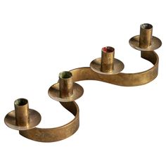 three brass candlesticks with one candle on each side and the other in different shapes