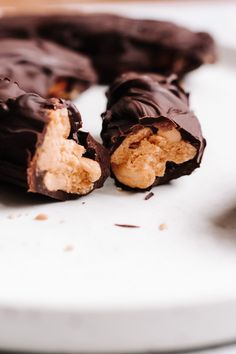 chocolate covered desserts on a white plate with one cut in half and the other partially eaten