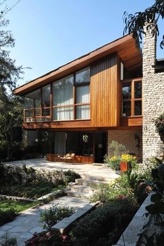 a house that is made out of wood and stone with lots of plants around it