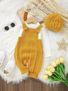 a baby's outfit, hat and shoes are laid out on a fur rug