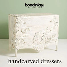 a white dresser sitting on top of a white floor next to a green wall with the words handcarved dressers written below it