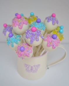 there are cupcakes with sprinkles on them sitting in a mug