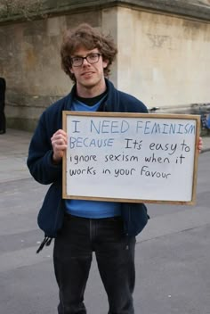 a man holding a sign that says i need feminist because pretending to care gets me laid