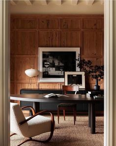 an office with wood paneling and chairs in the corner, along with a framed photograph on the wall