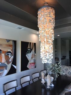 a chandelier hanging from the ceiling in a dining room with paintings on the wall