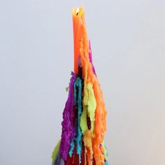 a multicolored candle is lit on a white surface