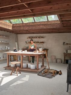 a woman is working in an art studio with her dog laying on the floor next to it