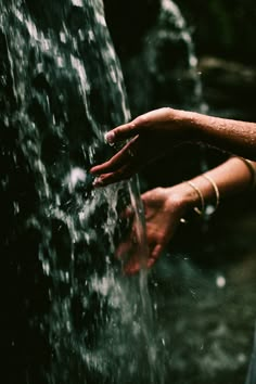 a woman's hand reaching into a water fountain