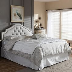 a white bed sitting in a bedroom on top of a hard wood floor next to a window