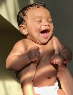 a baby is laughing while sitting in the sun