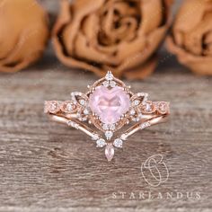 an engagement ring with a pink stone surrounded by white and rose gold diamonds on a wooden surface