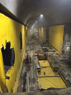 the inside of a tunnel under construction with yellow walls and scaffolding around it