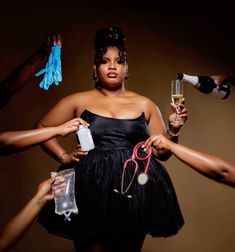 a woman in a black dress holding two wine glasses and a pair of blue gloves