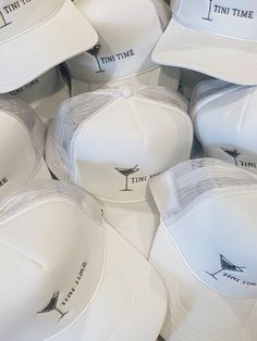 white hats with the words time and martinis printed on them are stacked up together