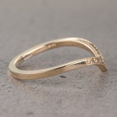 a yellow gold wedding band with an intricate design on the top and bottom, sitting on a gray surface