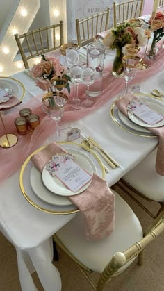 the table is set with pink and gold place settings