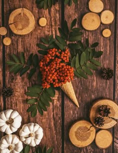 an arrangement of pumpkins, pine cones and other decorations on a wooden table top