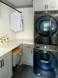 a washer and dryer in a small room with white tile flooring on the walls