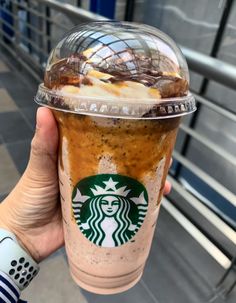 a person holding up a starbucks drink with ice cream and caramel on the top