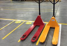 two red and yellow hand trucks sitting on top of a parking lot