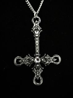 The Blasphemet is an artistic piece handcrafted in fine pewter, featuring a striking inverted cross design adorned with four demon heads and a Swarovski crystal in the color of your choice. This pendant comes with an 18-inch stainless steel chain, designed to be both hypoallergenic and durable. Made from high-quality materials, including 98% tin. The inverted cross measures 6.5 cm and each necklace is accompanied by a certificate of authenticity, confirming that it has been entirely handcrafted Gunmetal Cross Metal Jewelry, Medieval Cross Metal Jewelry, Medieval Silver Cross Jewelry, Gothic Cross Pendant With Oxidized Finish, Gothic Oxidized Cross Pendant Jewelry, Silver Gothic Crucifix Jewelry, Sandra Core, Religion Aesthetic, Satanic Jewelry