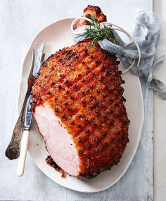 a piece of meat on a white plate with a fork and knife next to it