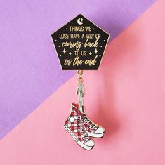 a pin with an image of a shoe hanging from it's side on a pink and purple background